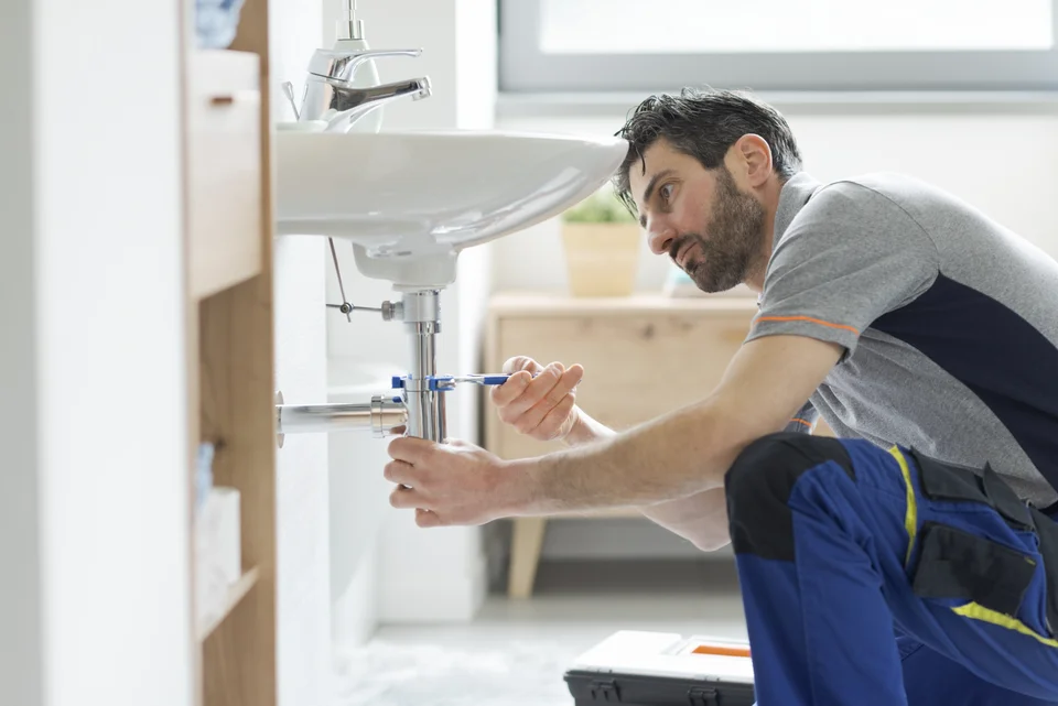 Plombier intervenant sur le siphon d’un lavabo